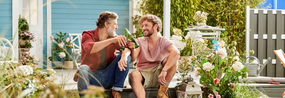 Zwei Personen stoßen mit Flaschen an